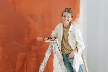 Nainen hymyilee maalatun seinän edessä.