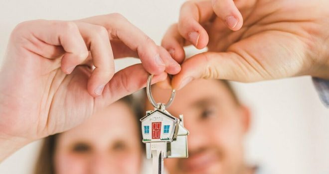 Mies ja nainen pitelevät talonmuotoista avaimenperää. Kiinteistömaailma myy asuntoja