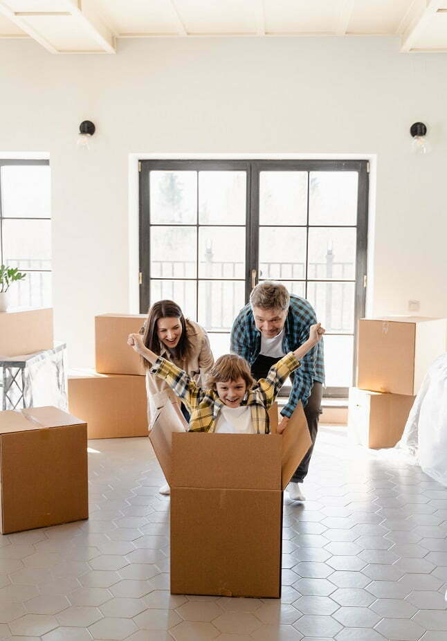 Lapsi istuu laatikossa muuttohetkellä. Kiinteistömaailma myy asuntoja.