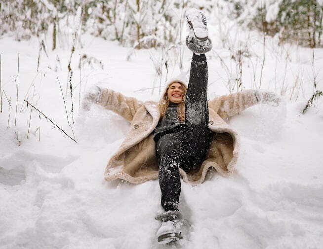 nainen makaa lumessa ja nauraa