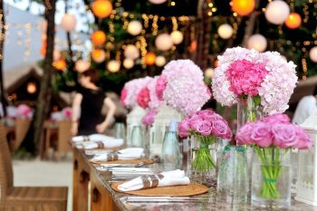 Vaaleanpunaisia kukkia juhlapöydässä.