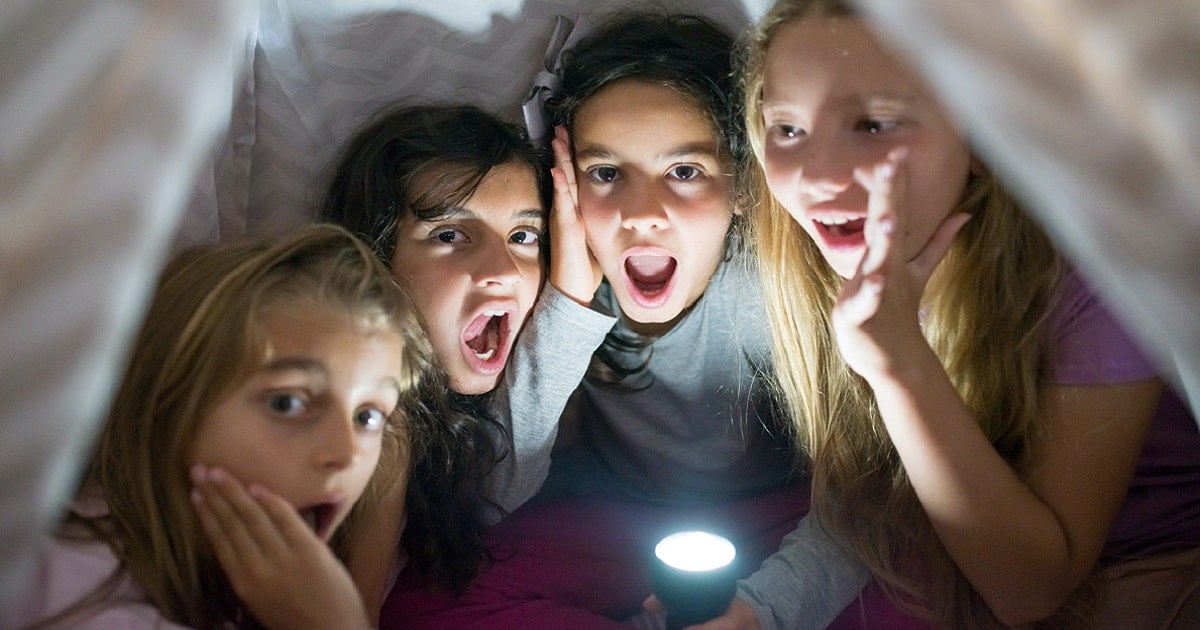 Lapset jännittävät teltassa taskulampun valossa sähkökatkoihin varautuminen -jutun kuvassa.