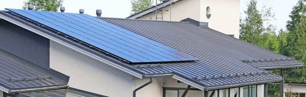 Aurinkopaneelit on asennettu mustalle peltikatolle, jolle on tehty kattohuolto.