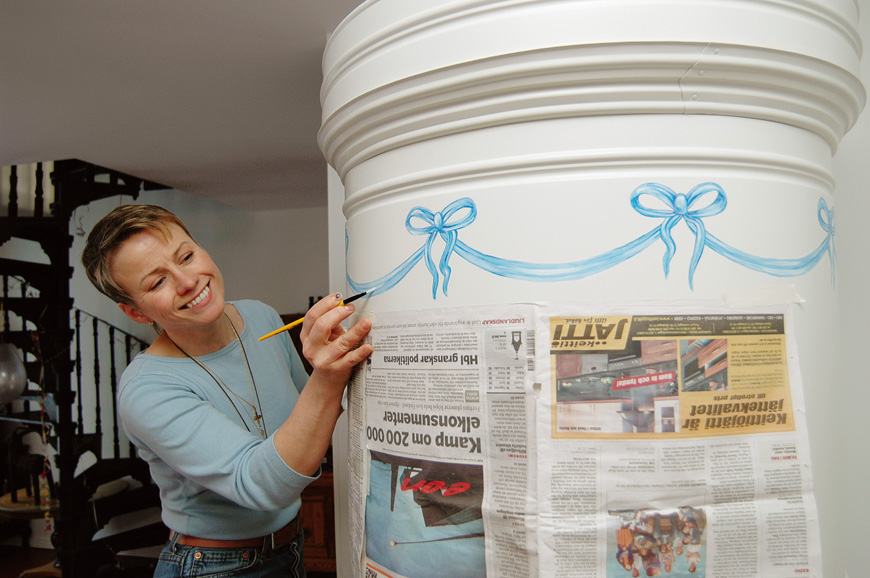 Pönttöuunin voi somistaa vaikka maalaamalla. Kuvittaja-somistaja Camilla Paro loihti uunin yläosaan rusettikranssin. Kaunis sininen väri toistuu Doddien kodissa muuallakin.