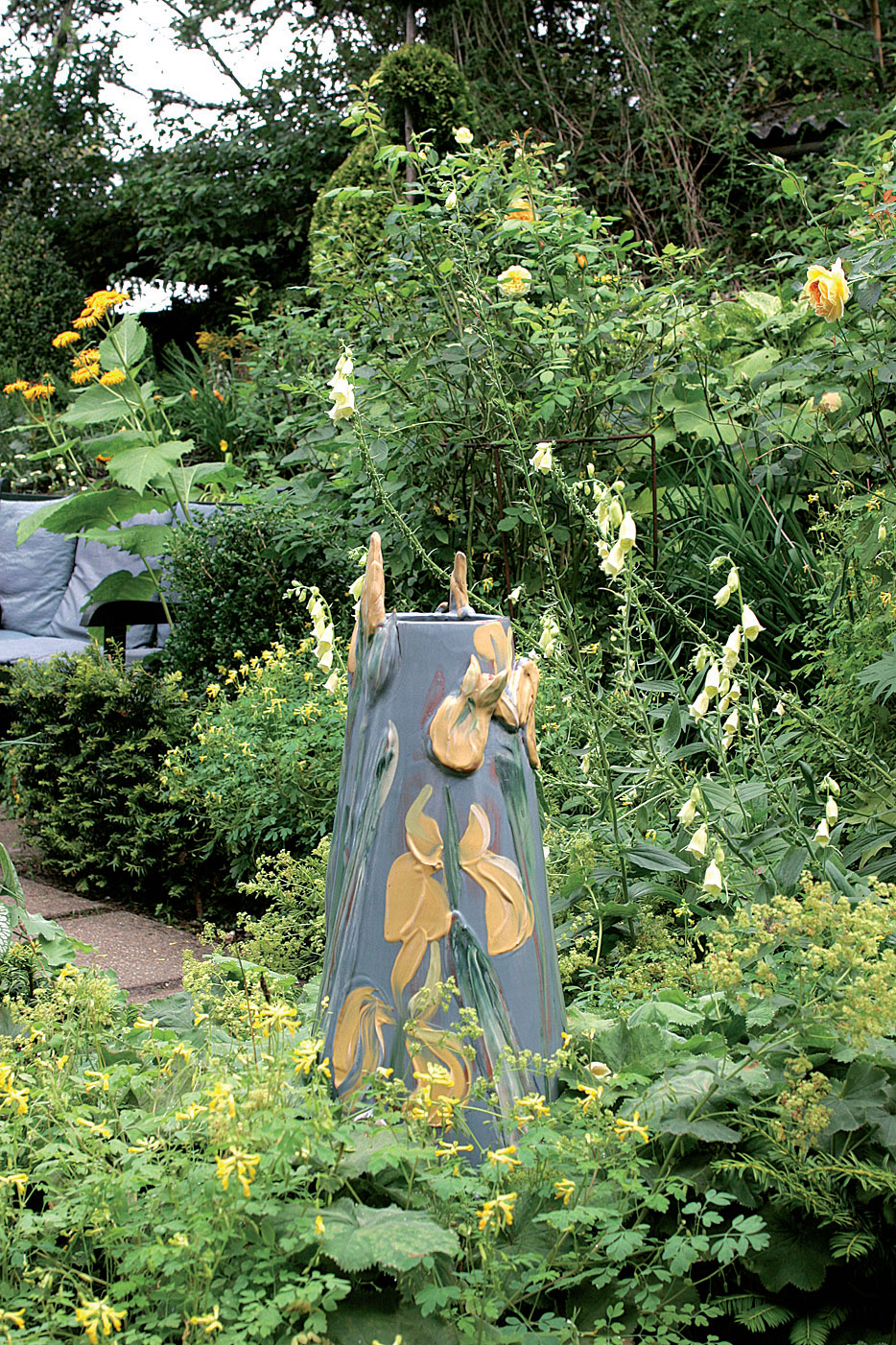 Keramiikkamaljakko pääsee oikeuksiinsa keltaisessa puutarhassa. Anne vie työnsä ammattikeraamikolle poltettaviksi. Jättipoimulehti (Alchemilla mollis) ja keltasormustinkukka (Digitalis grandiflora) ympäröivät teosta. 